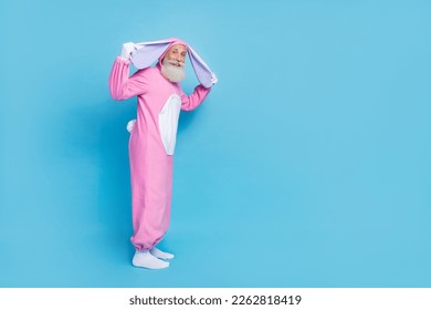 Full length photo of funky positive good mood senior man dressed pink rabbit costume arms hold ears isolated on blue color background