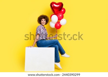 Full length photo of funky sweet woman wear print shirt sitting cube holding balloons bunch empty space isolated yellow color background
