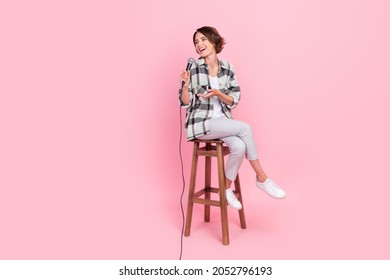 Full length photo of funky young brunette lady sit talk wear shirt trousers isolated on pink background