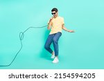 Full length photo of funny brunet young guy sing wear glasses t-shirt jeans footwear isolated on turquoise background