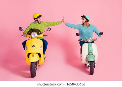 Full length photo of funny cheerful lady guy driving two vintage moped spend vacation together clapping arms one team wear casual sweater headgear isolated pink color background