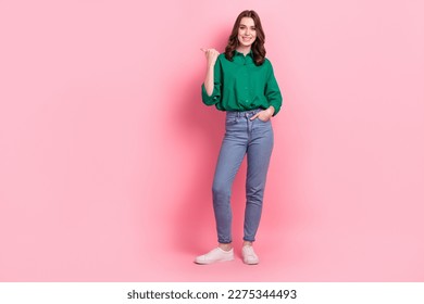 Full length photo of funny cute lady dressed green blouse pointing thumb emtpy space isolated pink color background