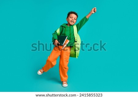 Full length photo of funny cute schoolboy dressed green pullover backpack hold book catching object isolated on teal color background