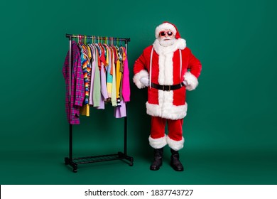 Full length photo funny funky santa claus x-mas shopping mall assistant ready help choose assortment wardrobe garment wear costume cap headwear boots belt isolated green color background - Powered by Shutterstock