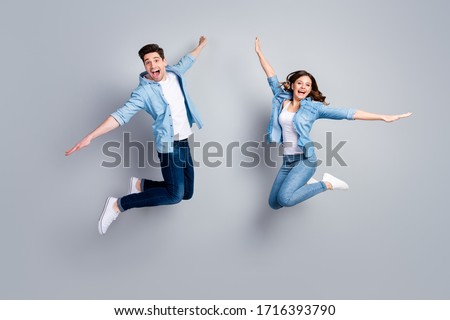 Full length photo of funny lady handsome guy crazy two people jumping high up spread hands like wings flying away wear casual denim shirts outfit isolated grey color background