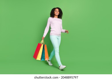 Full length photo of funny millennial brunette lady hold bags go wear sweater pants sneakers isolated on blue background