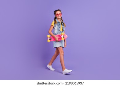 Full Length Photo Of Funny School Blond Girl Go Hold Skate Wear Glasses T-shirt Vest Skirt Shoes Isolated On Purple Background