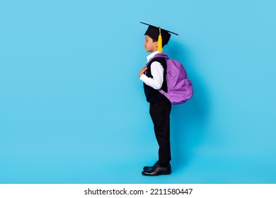 Full Length Photo Of Funny Sweet Little Guy Dressed Black Vest Mortarboard Rucksack Looking Empty Space Isolated Blue Color Background