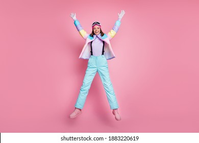 Full length photo of funny woman skier dressed colorful windbreaker eyeglasses jumping isolated pink color background