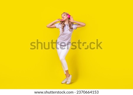 Full length photo of gorgeous pretty woman dressed purple t-shirt enjoy stereo sound in headphones isolated on yellow color background