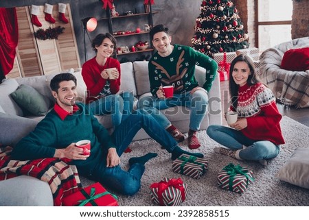 Full length photo of group funny fellows sitting sofa carpet floor enjoy cacao mug magic new year time indoors