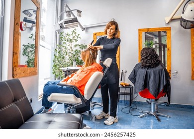 Full length photo of a hairdresser combing the hair of a client in the salon - Powered by Shutterstock