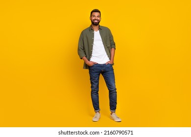 Full length photo of handsome cheerful guy dressed green shirt arms pockets walking isolated yellow color background - Powered by Shutterstock