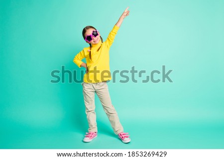 Full length photo of happy brown haired cheerful little girl wear star glasses make pose isolated on teal color background