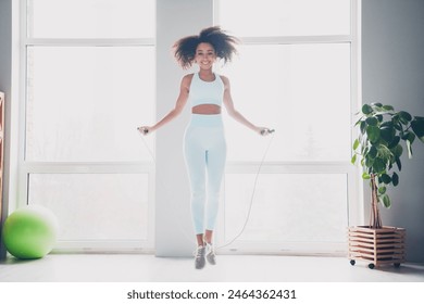 Full length photo of happy smiling lady activewear jumping rope indoors room home house - Powered by Shutterstock