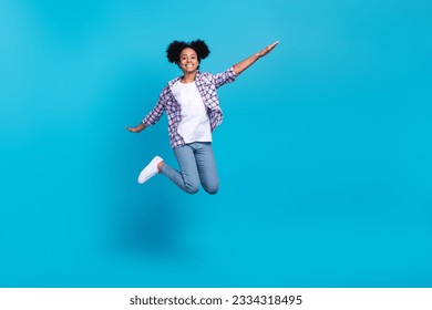 Full length photo of impressed carefree lady wear plaid shirt jumping high empty space isolated blue color background - Powered by Shutterstock