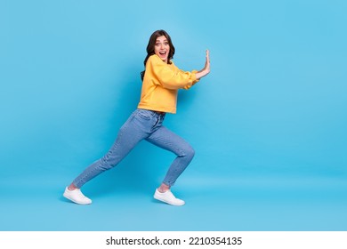 Full Length Photo Of Impressed Excited Lady Wear Yellow Sweater Pulling Big Empty Space Isolated Blue Color Background