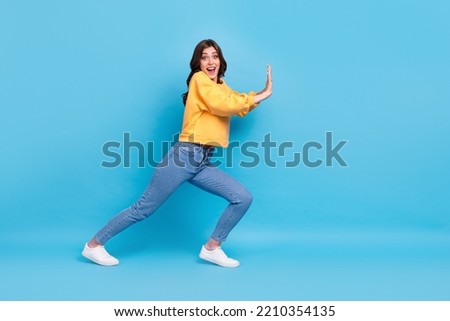 Full length photo of impressed excited lady wear yellow sweater pulling big empty space isolated blue color background