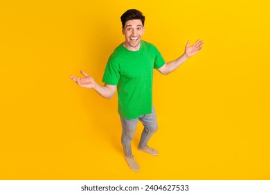 Full length photo of impressed man dressed green t-shirt jeans plams present objects empty space isolated on yellow color background