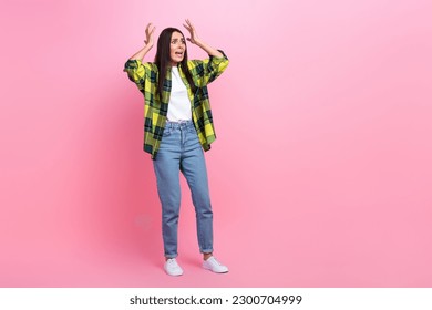 Full length photo of impressed scared lady wear checkered jacket rising arms hand looking empty space isolated pink color background