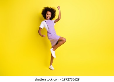 Full Length Photo Of Little Girl Raise Fist Open Mouth Wear Violet Overall Isolated Yellow Color Background