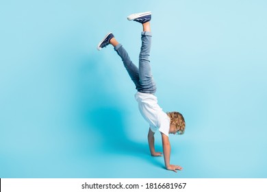 Full length photo of little kid stand hands raise legs wear white shirt jeans sneakers isolated blue color background - Powered by Shutterstock