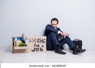 Full Length Photo Of Loser Worker Mature Guy Jobless Handmade Placard Search Work Sit Floor Briefcase Belongings Box Lost Success Career Crash Wear Suit Shoes Isolated Grey Background