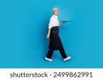 Full length photo of lovely pensioner lady walk tray serve clients coffee shop dressed waitress uniform isolated on blue color background