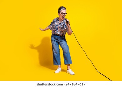 Full length photo of lovely senior lady sing loud microphone dressed stylish colorful garment isolated on yellow color background - Powered by Shutterstock