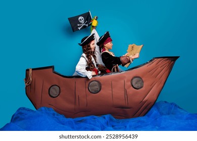 Full length photo of lovely two little kids hold treasure map wear pirates costumes birthday party playing ship isolated on blue background - Powered by Shutterstock