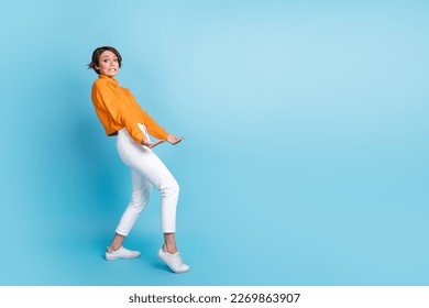 Full length photo of lovely young lady carry hold heavy empty space wear trendy orange clothes isolated on blue color background - Powered by Shutterstock