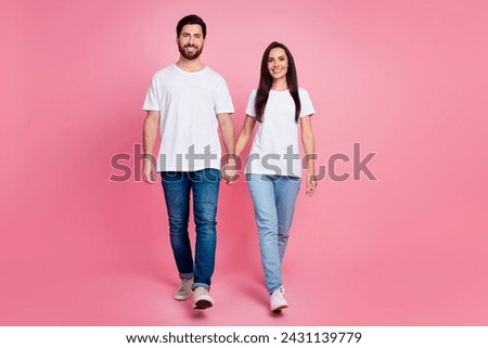 Full length photo of lovely young couple hold hands walking dating wear trendy white outfit isolated on pink color background