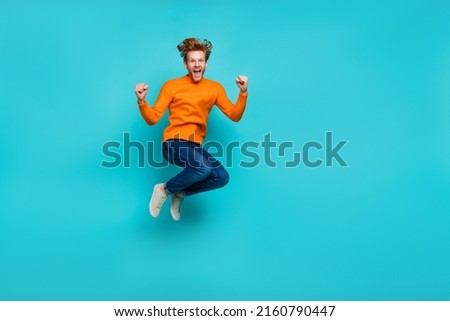 Full length photo of lucky impressed guy dressed orange sweater jumping high empty space isolated turquoise color background