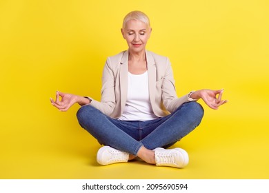 Full Length Photo Of Mature Lady Sit Floor Lotus Pose Meditate Yoga Asana Isolated Over Yellow Color Background