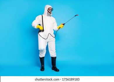 Full length photo of medical worker man use sprayer equipment disinfect copyspace covid infection spread wear latex gloves biohazard suit boots isolated over blue color background