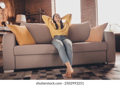 Full length photo of nice teen lady sit couch relax hands behind head dressed yellow garment spend pastime spacious house indoors room - Powered by Shutterstock