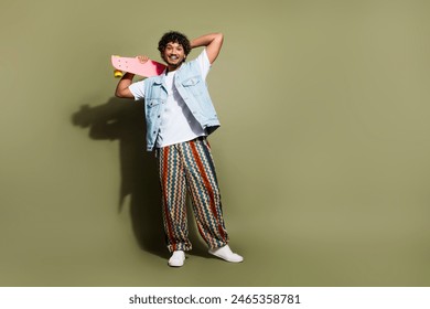 Full length photo of nice young male hold skateboard have fun dressed stylish denim garment isolated on khaki color background - Powered by Shutterstock