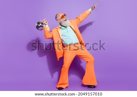 Full length photo of old positive happy man hold disco ball point look empty space isolated on purple color background