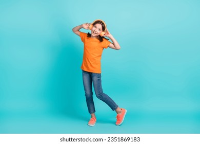 Full length photo of optimistic meloman wear orange trendy clothes use wireless gadget look empty space isolated on cyan color background - Powered by Shutterstock