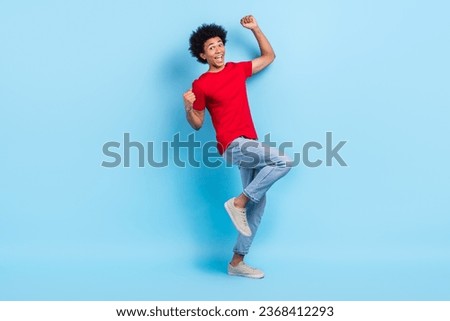 Full length photo of overjoyed ecstatic person wear red t-shirt denim trousers hands up win gambling isolated on blue color background