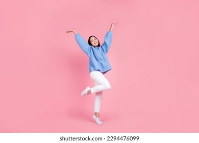 Full length photo of pleasant nice girl wear blue sweater white pants arms demonstrate empty space isolated on pink color background - Powered by Shutterstock