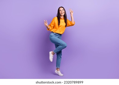 Full length photo of pleasant optimistic girl dressed yellow shirt pants showing v-sign symbol isolated on purple color background
