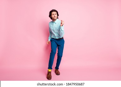 Full length photo portrait of carefree guy dancing snapping fingers isolated on pastel pink colored background with blank space