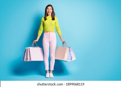 Full length photo portrait of screaming woman holding shopping bags looking at blank space isolated on pastel blue colored background