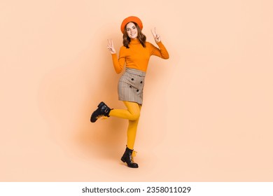 Full length photo of positive adorable lady dressed stylish bright clothes hands demonstrate v-sign isolated on beige color background