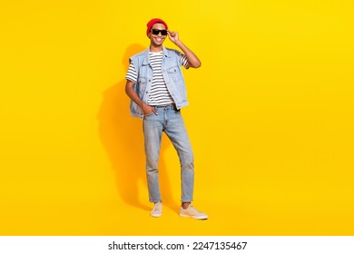 Full length photo of positive cheerful man wear jeans outfit dark glasses smiling walking empty space isolated yellow color background - Powered by Shutterstock