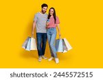 Full length photo of positive couple guy with shopping bags look at smartphone read notification isolated on yellow color background