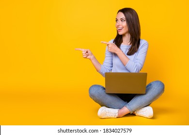 Full length photo of positive girl sit floor legs crossed work remote laptop indicate online ads promo wear purple violet sweater denim jeans isolated over bright shine color background