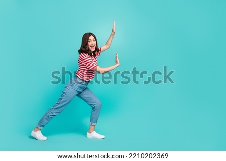 Full length photo of positive lady hold empty space push imaginary stone large product isolated on aquamarine color background