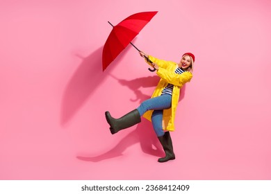 Full length photo of pretty excited woman dressed rain coat walking under parasol air blowing empty space isolated pink color background - Powered by Shutterstock